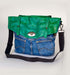 Stylish green leather and denim handbag with dual pockets and adjustable strap.